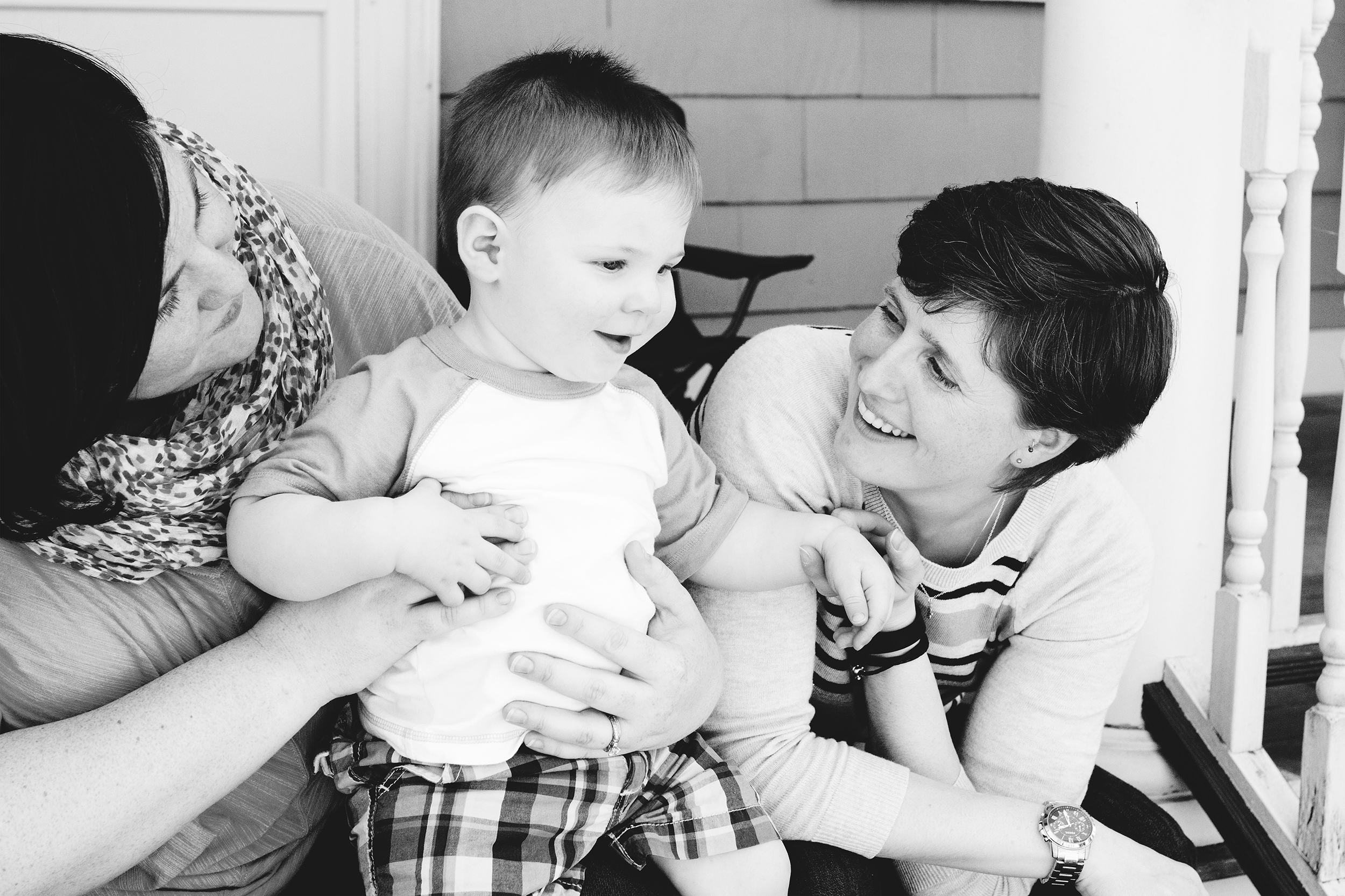 two moms same sex family with their toddler little boy at home on front porch