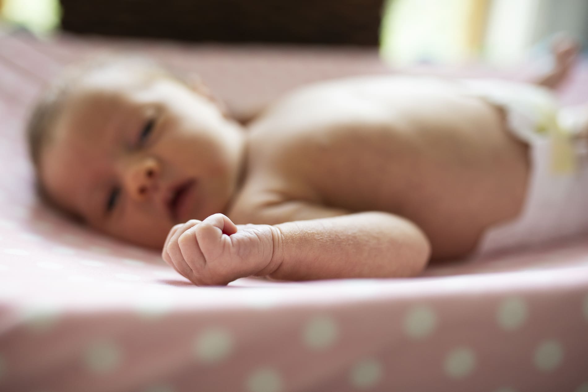 newborn baby girl looking at her hand fist macro details