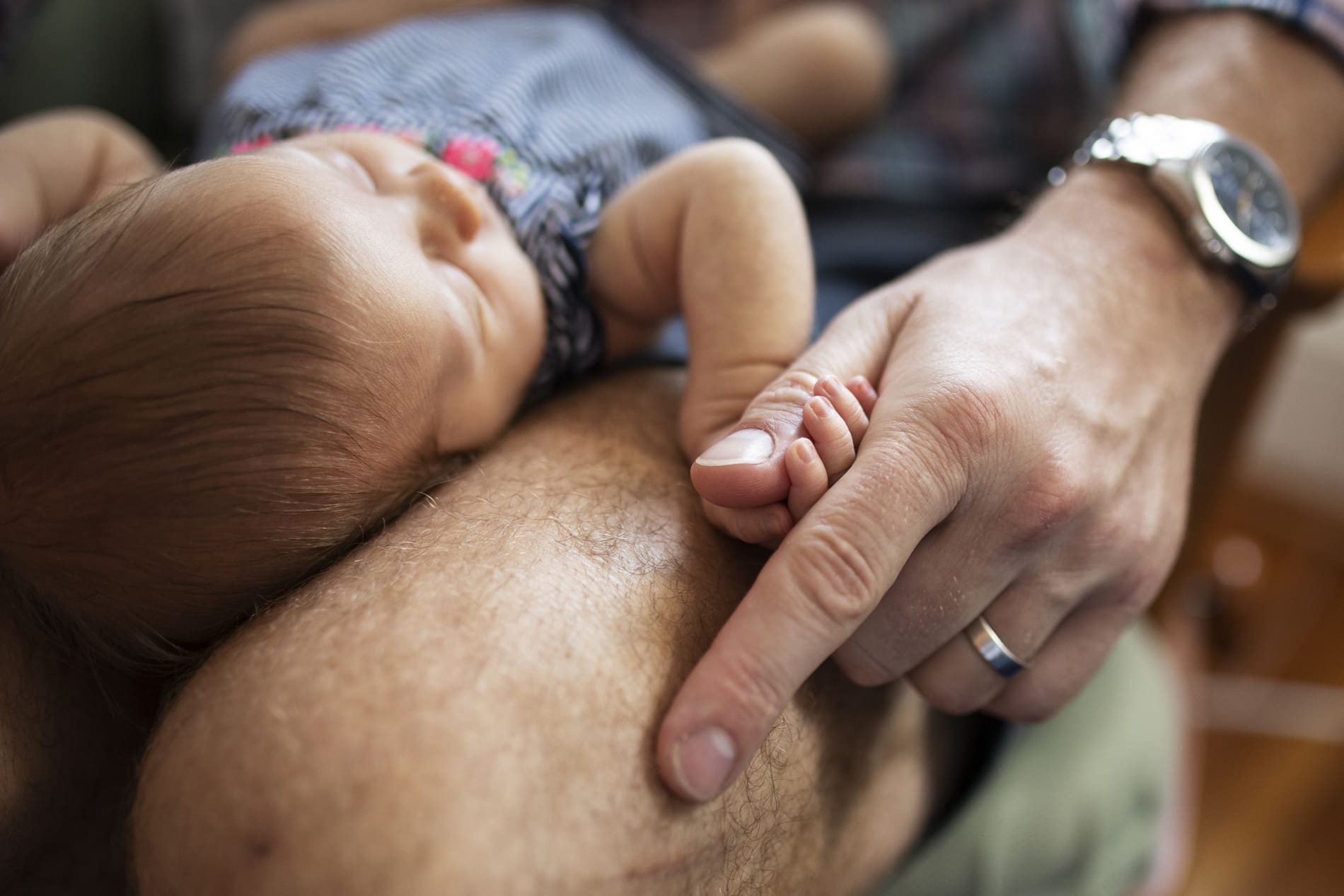 newborn baby girl holds dad thumb hand macro detail