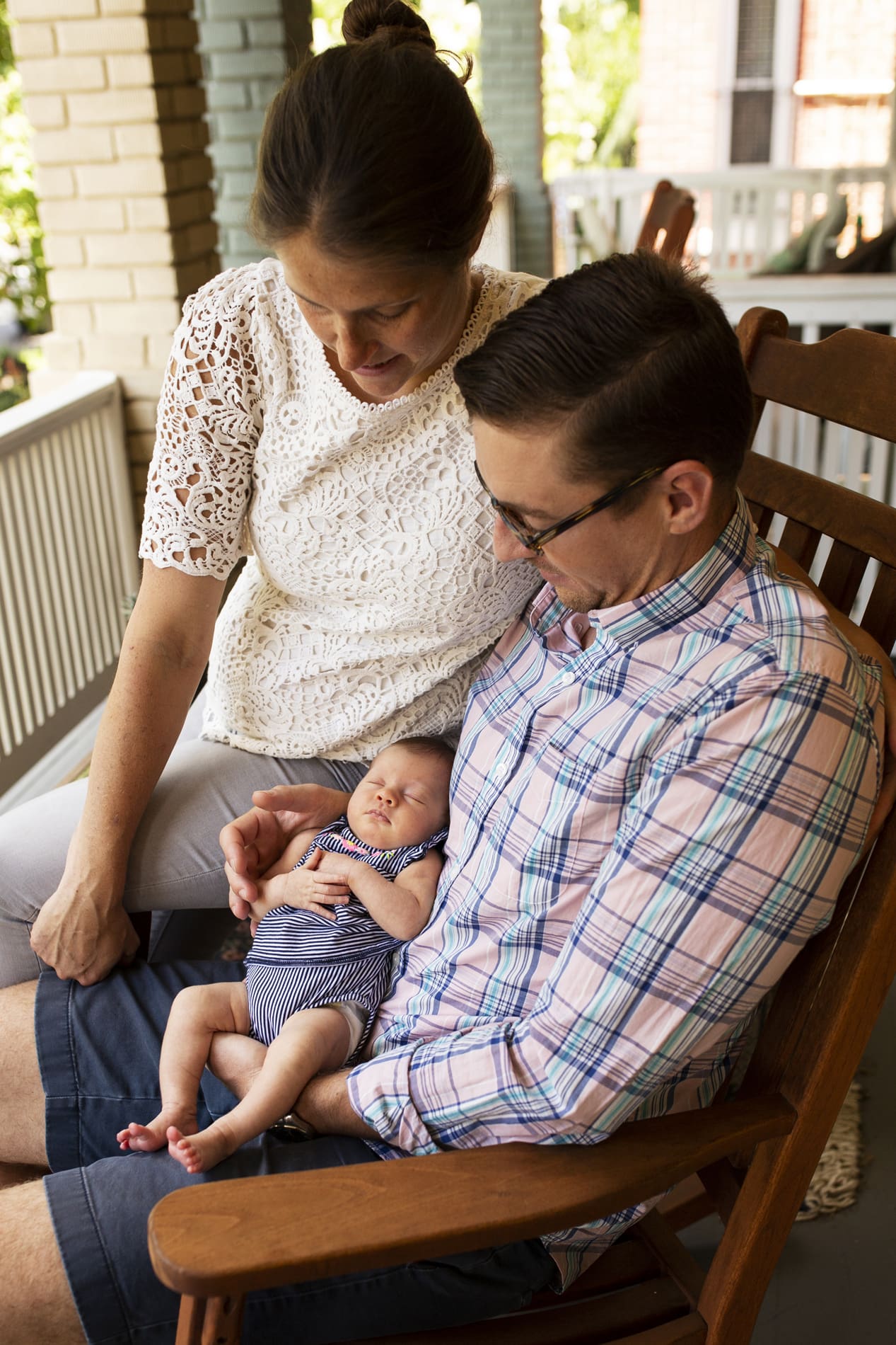 parents couple holding newborn baby girl front porch