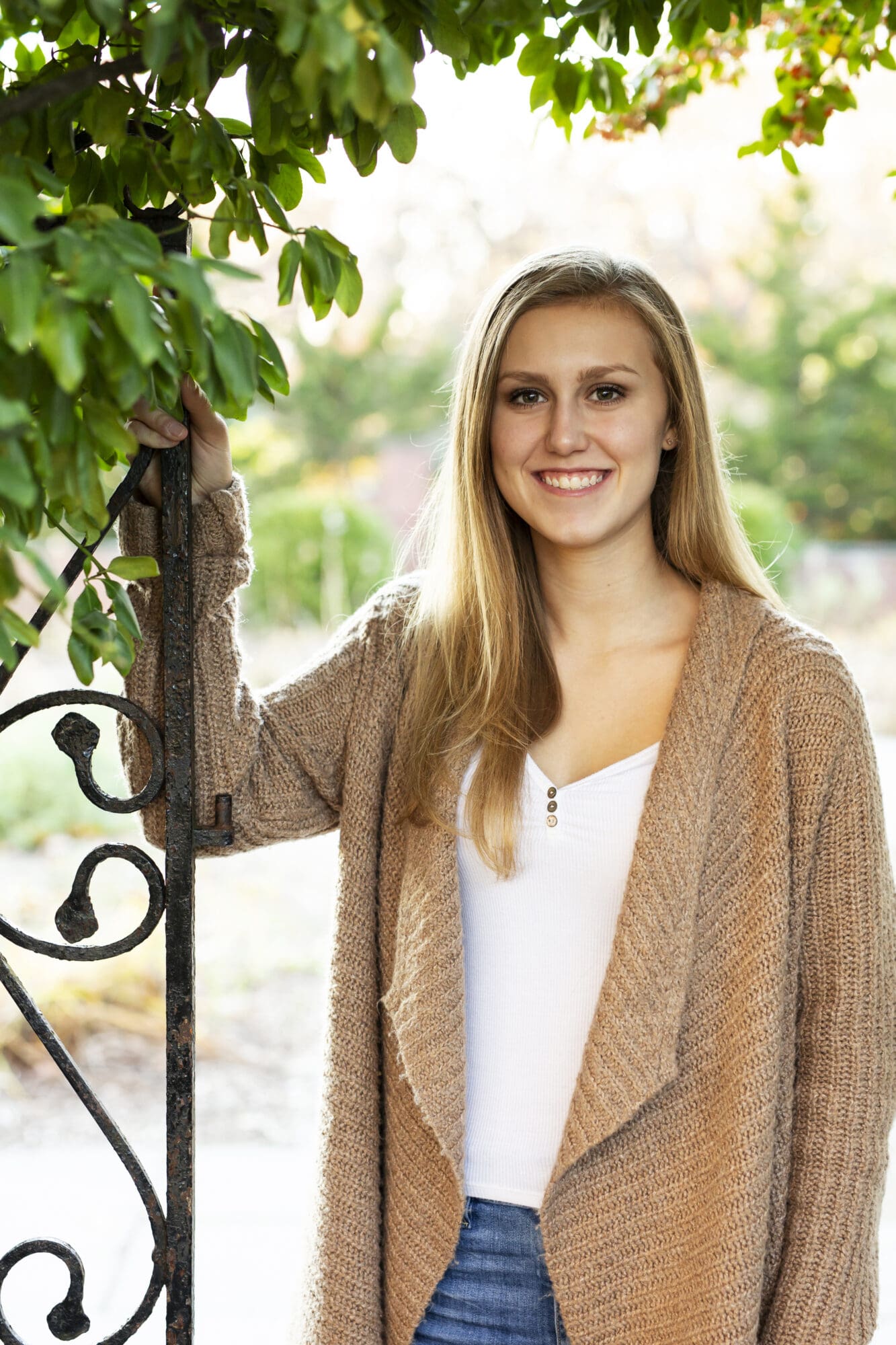 senior girl portrait in garden with metal gate and leaves